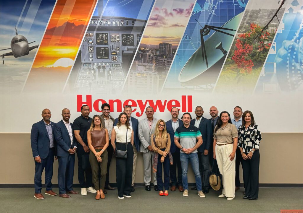 Group of site selectors and InvestPR staff posing in front of a wall with aerospace visuals and the Honeywell logo.